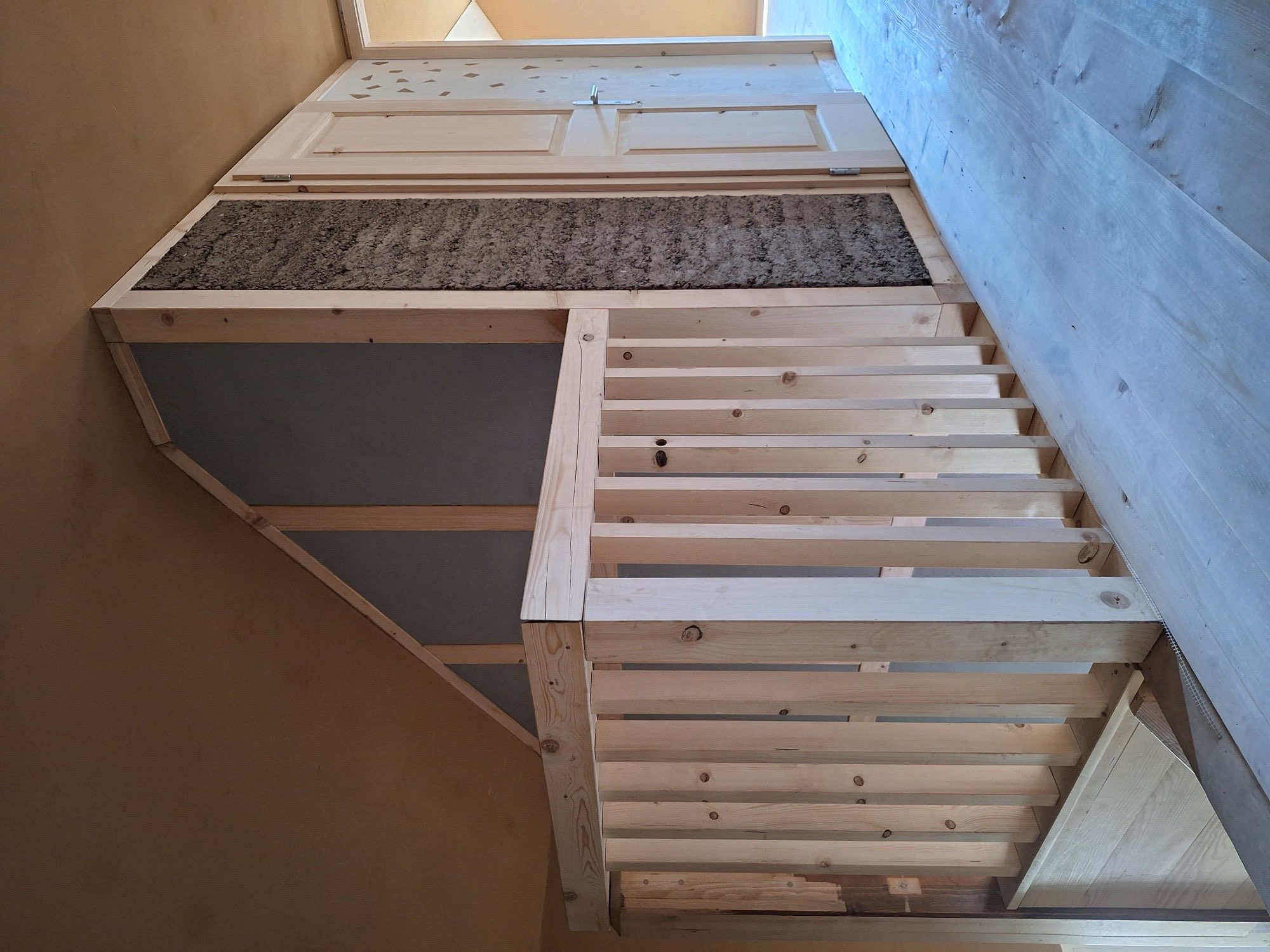 Treppe mit Holzgeländer und Lehmwand